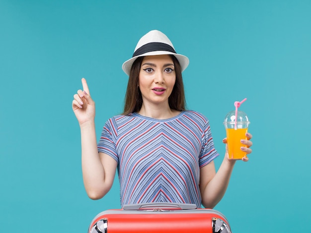 Vooraanzicht vrouw in vakantie met haar rode tas met haar sap op blauwe bureau reis reis vakantie vrouwelijke reis