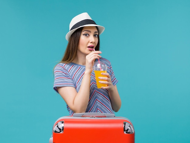 Vooraanzicht vrouw in vakantie met haar rode zak met haar sap op lichtblauwe achtergrond reis reis reis vakantie vrouw