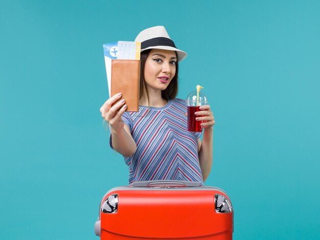 Vooraanzicht vrouw in vakantie met kaartjes en rood sap op de blauwe achtergrond zeereis reis vrouwelijke vakantie