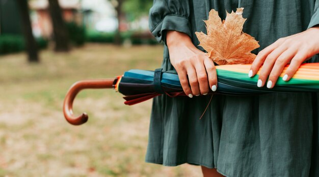 Vooraanzicht vrouw met bladeren en een kleurrijke paraplu met kopie ruimte