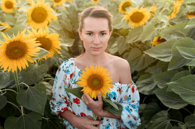 Vooraanzicht vrouw poseren in zonnebloem veld