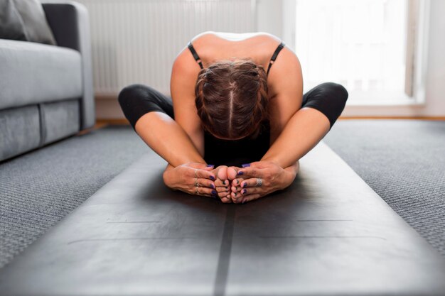 Vooraanzicht vrouw zitten en rekken op yoga mat