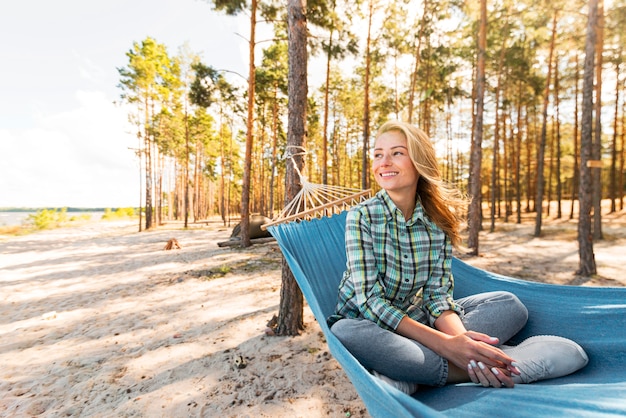 Vooraanzicht vrouw zittend in een hangmat en wegkijken