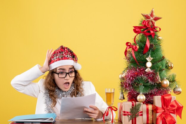 Vooraanzicht vrouwelijke arts achter haar tafel met documenten