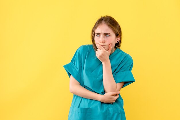 Vooraanzicht vrouwelijke arts denken op gele achtergrond medic emotie ziekenhuis gezondheid