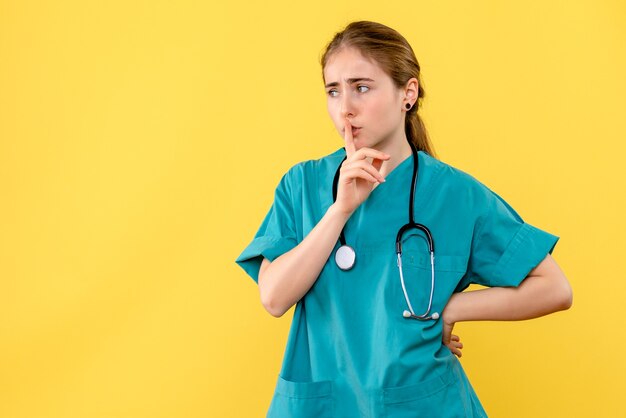 Vooraanzicht vrouwelijke arts die vraagt om te zwijgen over gele achtergrond emotie ziekenhuisgezondheid