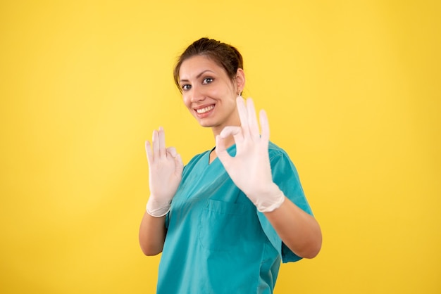 Vooraanzicht vrouwelijke arts in handschoenen op gele achtergrond