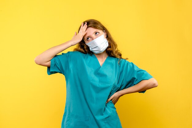 Vooraanzicht vrouwelijke arts in masker die op gele ruimte denken
