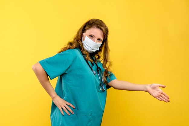 Vooraanzicht vrouwelijke arts in masker op gele ruimte