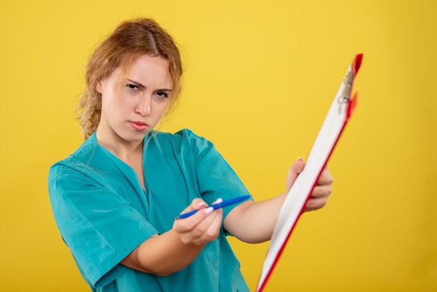 Gratis foto vooraanzicht vrouwelijke arts in medisch overhemd analyse, ziekenhuis kleur covid-19 gezondheid emotie te houden