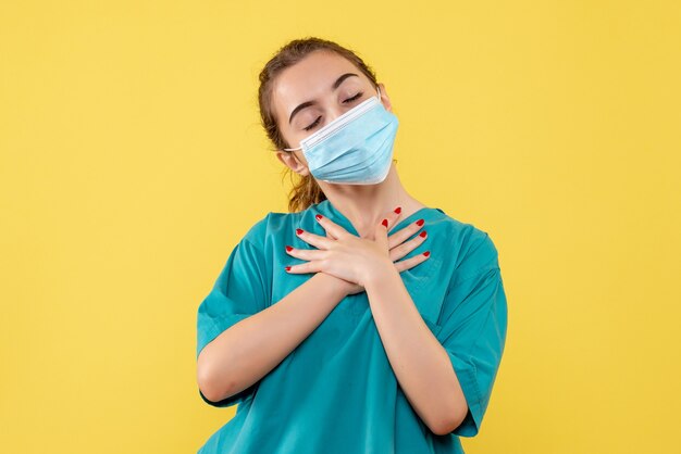 Vooraanzicht vrouwelijke arts in medisch overhemd en masker, gezondheid pandemie kleur covid-19 virus uniform