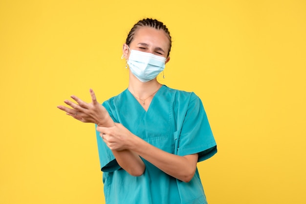 Vooraanzicht vrouwelijke arts in medisch overhemd en masker met gekwetste arm, gezondheidsverpleegkundige virus pandemie ziekenhuis covid-19 medic