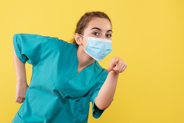 Vooraanzicht vrouwelijke arts in medisch overhemd en masker, virus pandemie uniform kleur covid-19 gezondheid coronavirus