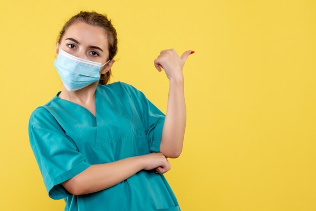 Vooraanzicht vrouwelijke arts in medisch overhemd en steriel masker, uniforme covid-19 coronavirus pandemie gezondheid