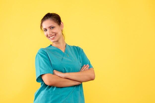 Vooraanzicht vrouwelijke arts in medisch overhemd glimlachend op gele achtergrond