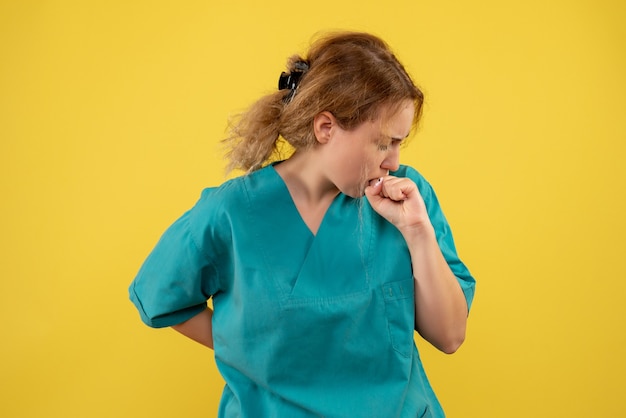 Gratis foto vooraanzicht vrouwelijke arts in medisch overhemd op geel bureau gezondheidsmedic covid-19 kleur ziekenhuisverpleegkundige