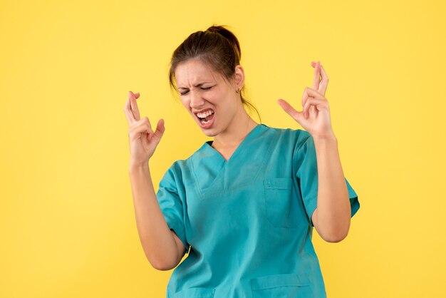 Vooraanzicht vrouwelijke arts in medisch overhemd op gele achtergrond