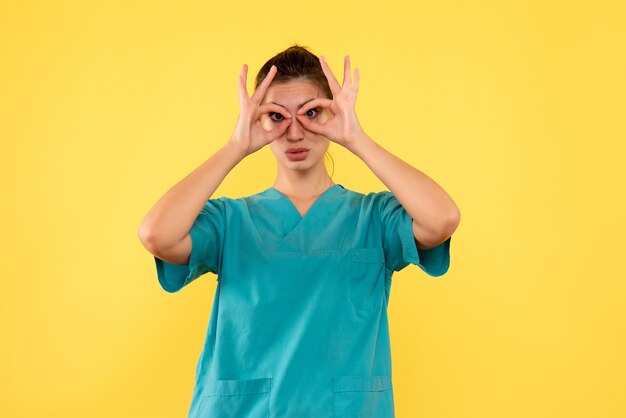 Vooraanzicht vrouwelijke arts in medisch overhemd op gele achtergrond
