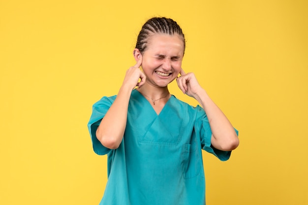 Vooraanzicht vrouwelijke arts in medisch overhemd voor haar oren, virus gezondheid emotie covid-19 kleur verpleegster ziekenhuis