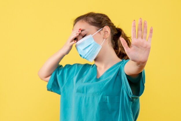 Vooraanzicht vrouwelijke arts in medisch shirt en masker benadrukt, gezondheidskleur pandemie virus covid-19 uniform coronavirus