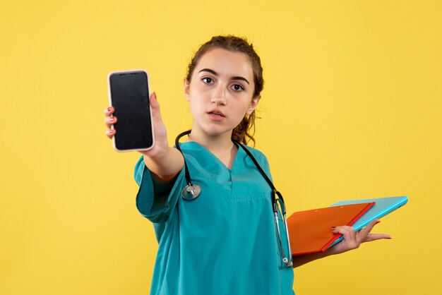 Vooraanzicht vrouwelijke arts in medisch shirt met notities en telefoon, gezondheid emotie uniform pandemisch covid-19-virus