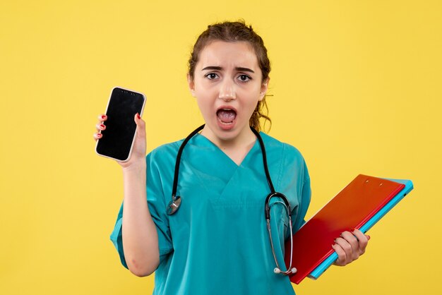 Vooraanzicht vrouwelijke arts in medisch shirt met notities en telefoon, virus gezondheid emotie uniform covid-19 pandemie