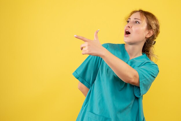 Vooraanzicht vrouwelijke arts in medisch shirt op geel bureau gezondheid verpleegkundige medic covid-19 kleur emotie