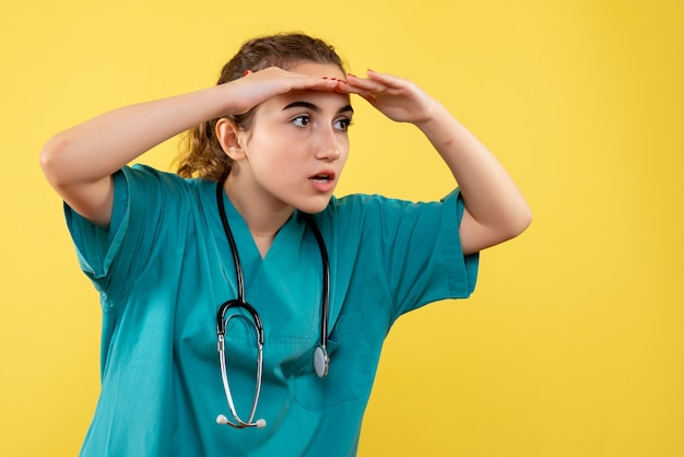 Vooraanzicht vrouwelijke arts in medisch shirt op geel bureau kleur emotie virus covid-19 uniforme gezondheid