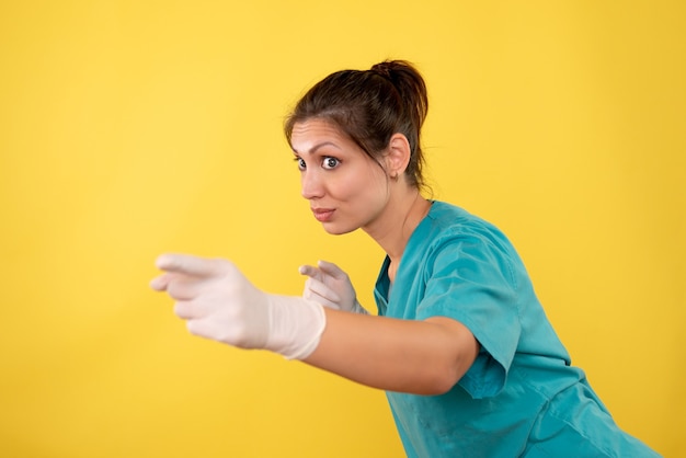 Vooraanzicht vrouwelijke arts in medische handschoenen op gele achtergrond