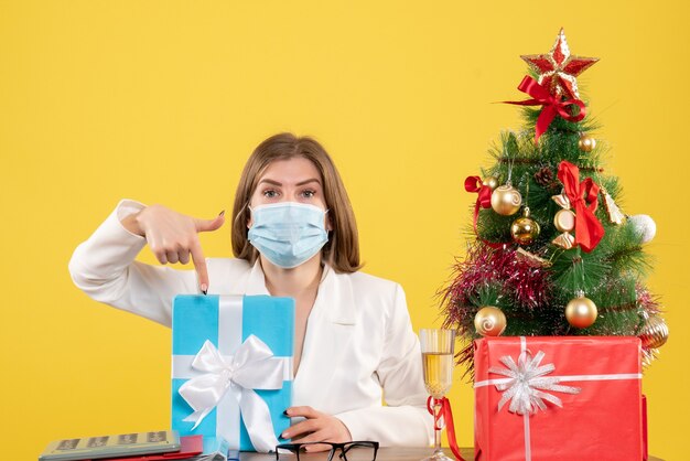 Vooraanzicht vrouwelijke arts in steriel masker met cadeautjes