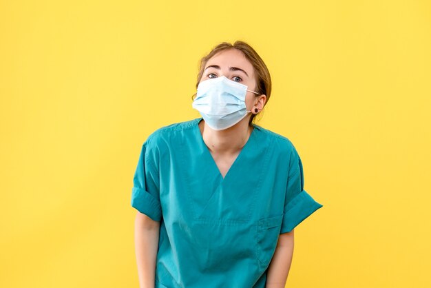 Vooraanzicht vrouwelijke arts in steriel masker op gele achtergrond gezondheidsvirus pandemie covid-