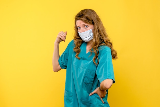 Vooraanzicht vrouwelijke arts in steriel masker op gele ruimte
