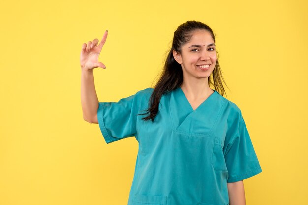 Vooraanzicht vrouwelijke arts in uniform met grootte met hand staan