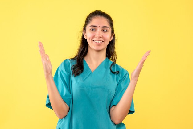 Vooraanzicht vrouwelijke arts in uniform verhogen handen staan