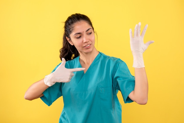 Vooraanzicht vrouwelijke arts met latexhandschoenen die met vinger haar hand richten