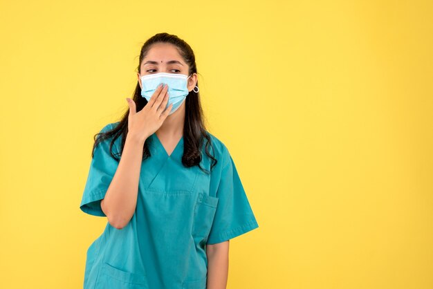 Vooraanzicht vrouwelijke arts met masker hand aan haar mond brengen