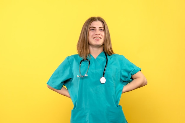 Vooraanzicht vrouwelijke arts poseren en glimlachend op gele ruimte