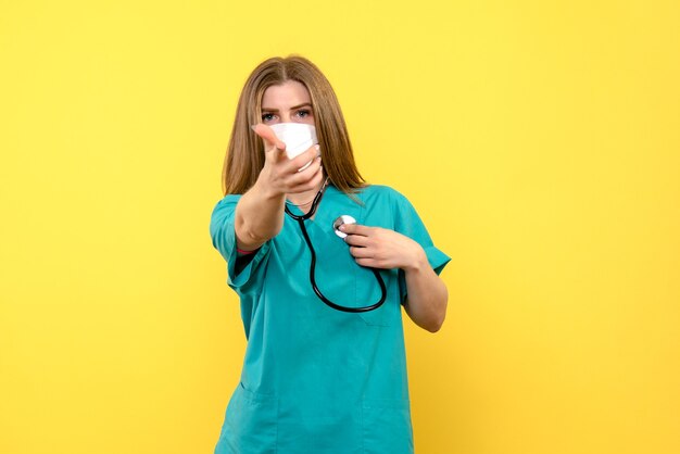 Vooraanzicht vrouwelijke arts steriel masker dragen op gele vloer emotie medisch ziekenhuis