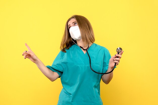 Vooraanzicht vrouwelijke arts steriel masker dragen op lichtgele ruimte