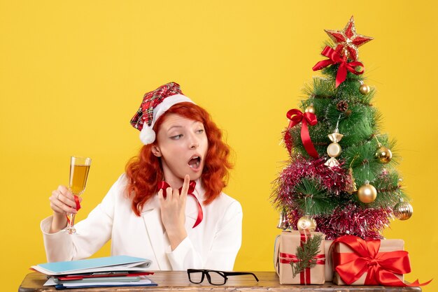 Vooraanzicht vrouwelijke arts zitten en vieren kerst met champagne