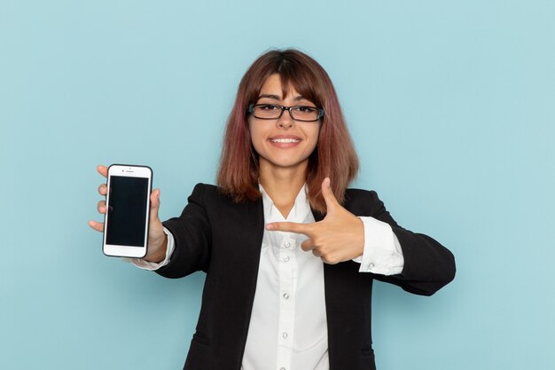 Vooraanzicht vrouwelijke beambte die haar telefoon op het blauwe oppervlak houdt