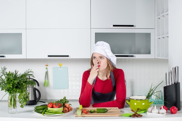 Vooraanzicht vrouwelijke chef-kok in koksmuts die aan iets denkt