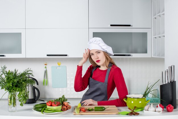 Vooraanzicht vrouwelijke chef-kok in koksmuts die haar hoofd met pijn vasthoudt