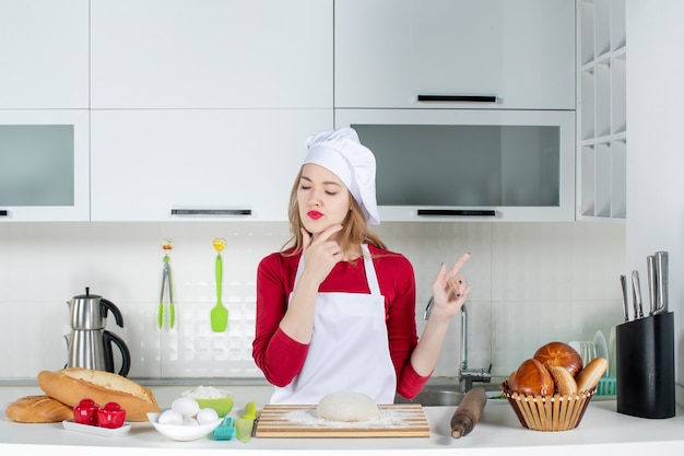 Vooraanzicht vrouwelijke chef-kok in uniform denken aan iets