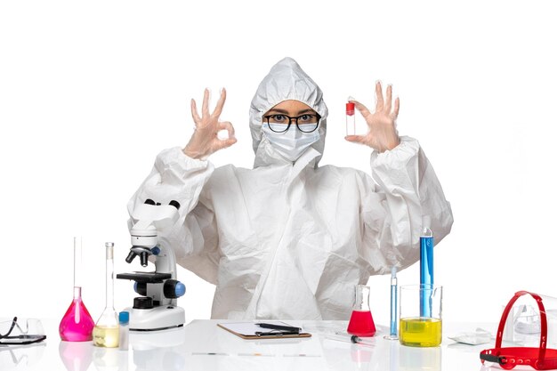 Vooraanzicht vrouwelijke chemicus in speciaal beschermend pak bedrijf kolf op lichte witte achtergrond virus gezondheid chemie covid-