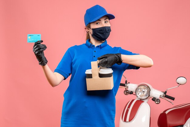 Vooraanzicht vrouwelijke koerier in masker met bezorgkoffie en bankkaart op roze