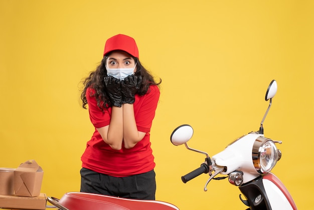 Vooraanzicht vrouwelijke koerier in rood uniform en masker op gele achtergrond covid- job service delivery worker pandemie