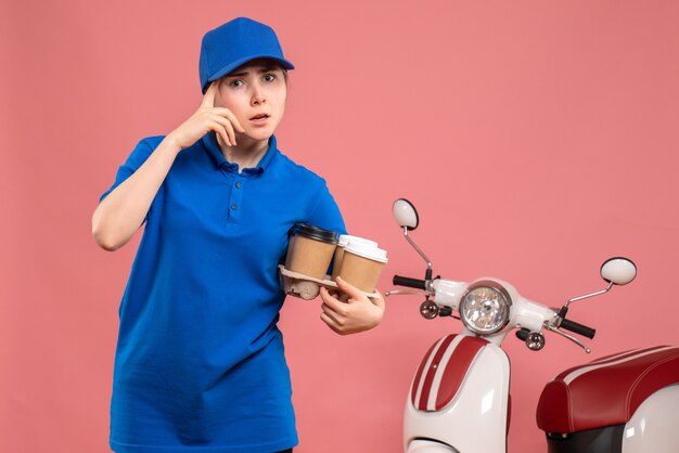 Vooraanzicht vrouwelijke koerier met bezorgkoffie op een roze werkbezorging uniform de fietsbaan van de dienstverlener