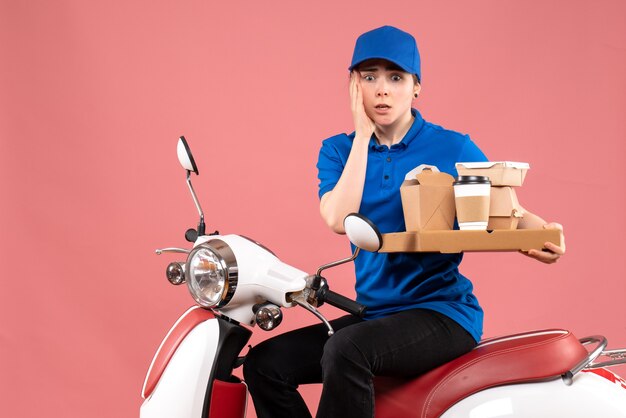 Vooraanzicht vrouwelijke koerier met voedselpakketten en dozen op roze jobkleuren werknemer voedsel levering fiets uniforme service