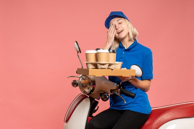 Vooraanzicht vrouwelijke koerier op fiets met koffiekopjes op roze